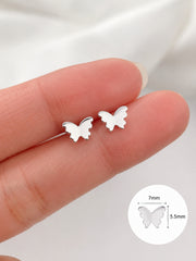 Silver butterfly earrings held between fingers with a close-up inset showing size measurement.