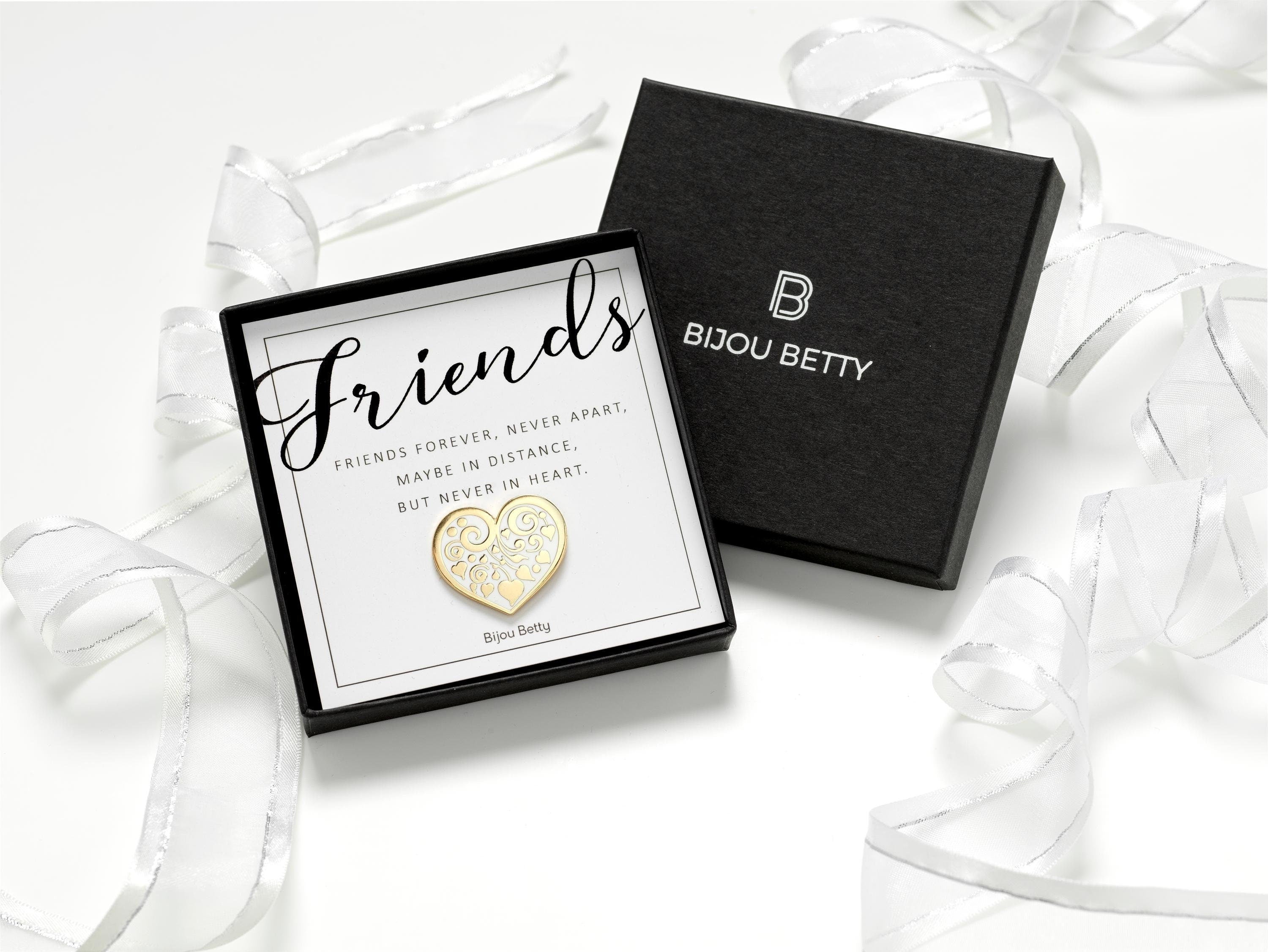 Gold-plated enamel heart pin badge with white floral motif, perfect friendship gift for birthdays, Christmas, or just because. Includes message card: Friends forever, never apart, maybe in distance, but never in heart; and optional gift box.