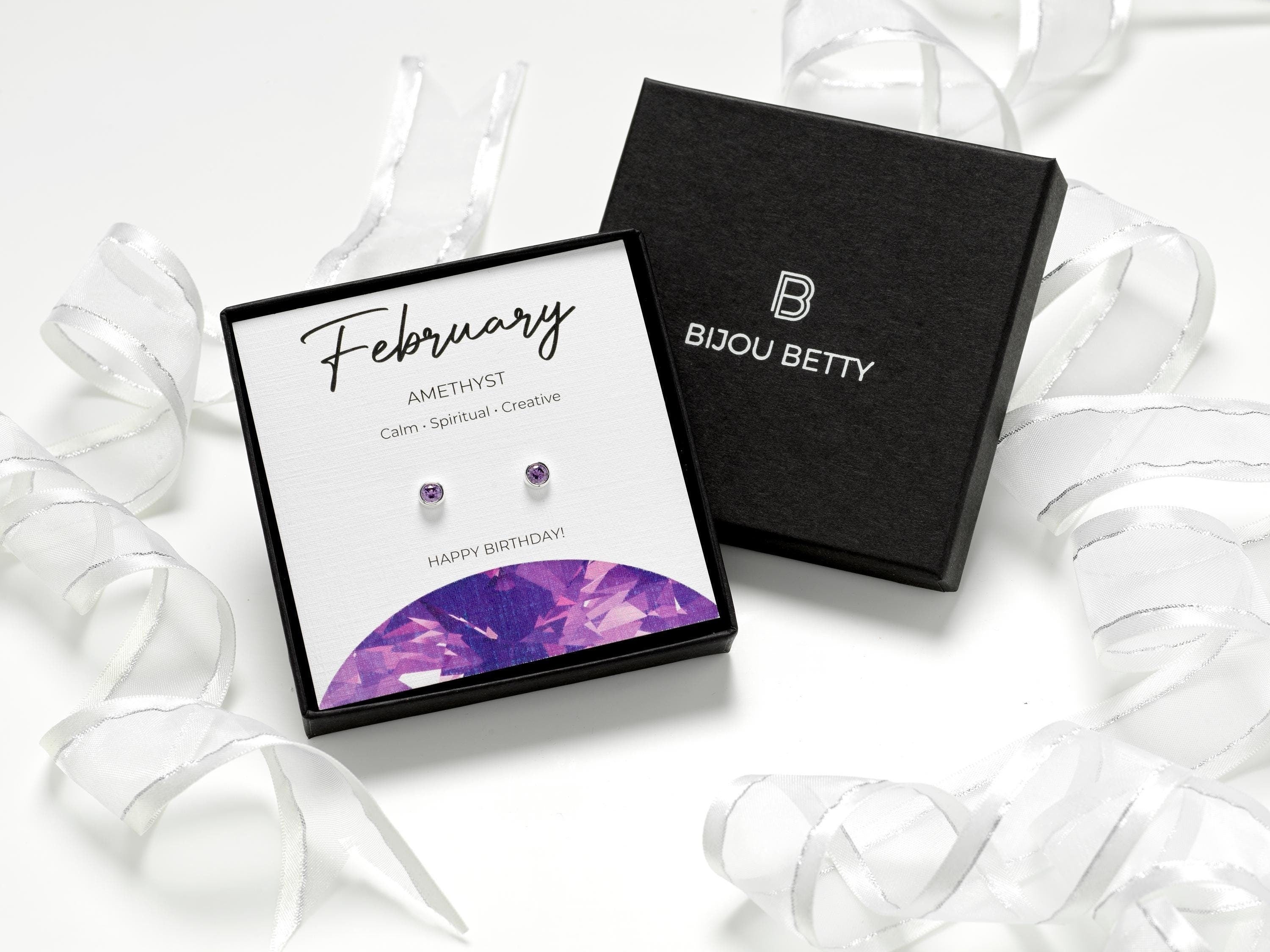 Sterling silver February birthstone earrings with 4mm amethyst cubic zirconia. Perfect gift for daughter, sister, granddaughter, niece, or friend. Includes gift box, bag, tissue, and card highlighting traits: calm, spiritual, creative.