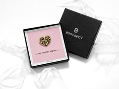 Bijou Betty’s new chapter pin gift set, with a gold-plated heart enamel pin on a card reading A New Chapter Begins, with tissue wrapping and optional gift box and bag.