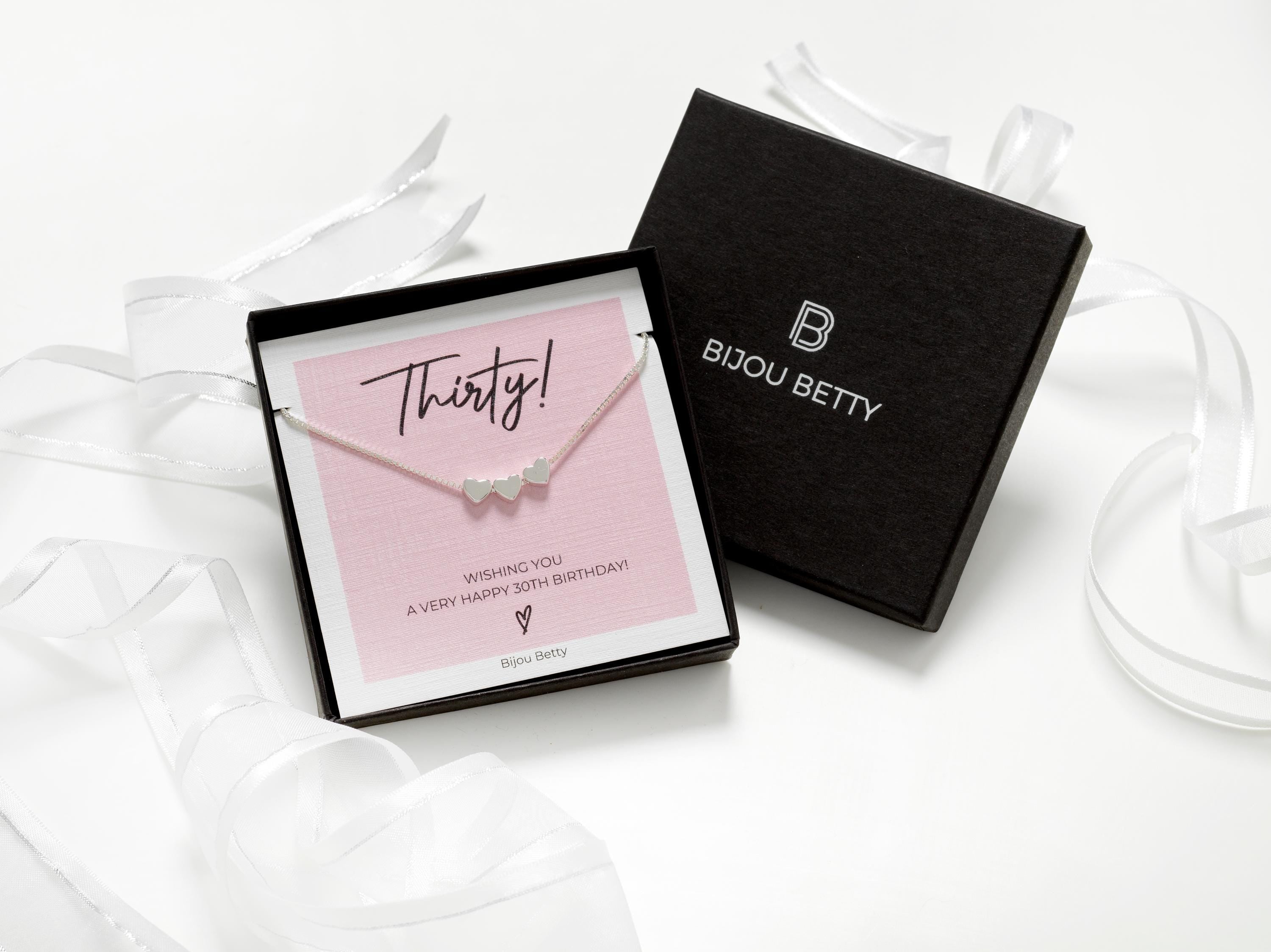 Bijou Betty’s 30th birthday necklace gift set, with a 925 sterling silver three-heart necklace, in a gift box with ribbon, tissue, and a card reading, Thirty! WISHING YOU A VERY HAPPY 30TH BIRTHDAY!