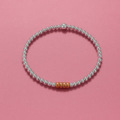 Close-up of Bijou Betty’s 925 silver and rose gold decades bracelet, 3mm silver beads, 4mm rose gold rings, stretch-fit.