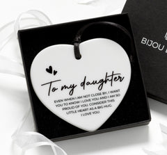 Close-up of Bijou Betty’s 75mm ceramic heart keepsake with black satin ribbon and daughter quote card, on white background.