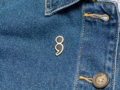 Black enamel pin on jacket, 25.5mm, Your Story Continues, Bijou Betty gift for friend’s new chapter.