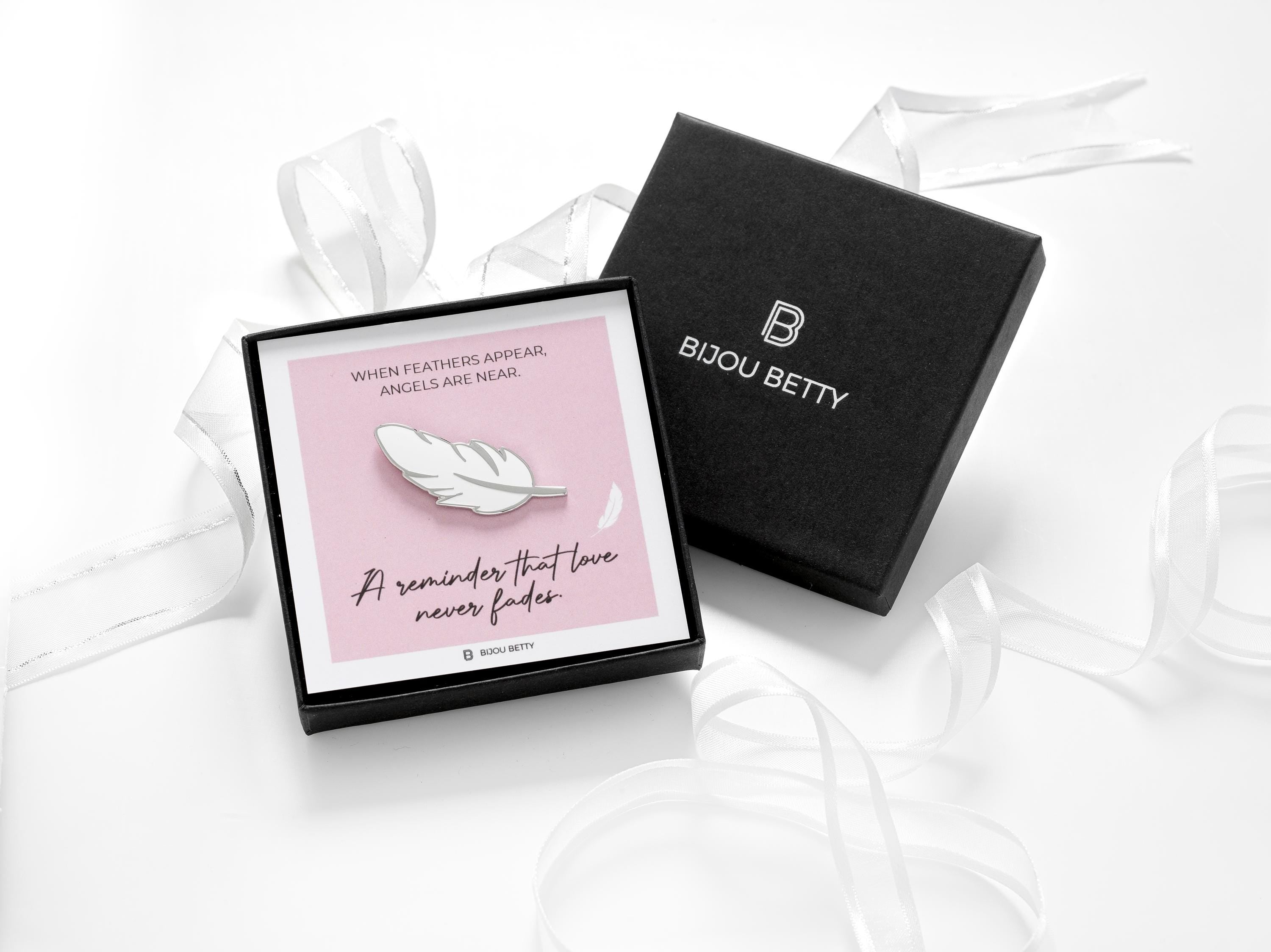 When feathers appear sympathy gift. A white feather enamel pin badge in a gift box.