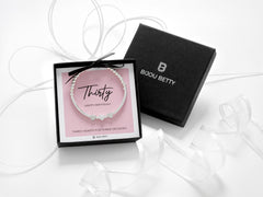 Sterling silver 30th birthday bracelet with three heart beads, dainty stretch design with polished silver beads, meaningful three decades gift for her, displayed on pink background, gift boxed jewellery by Bijou Betty