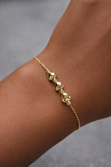 Gold bracelet on a wrist with a neutral background