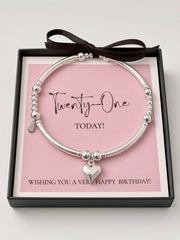 A silver beaded bangle bracelet with a heart charm, presented in a black gift box with a pink card that reads 'Twenty-One TODAY!' and 'Wishing you a very happy birthday!', tied with a black ribbon.