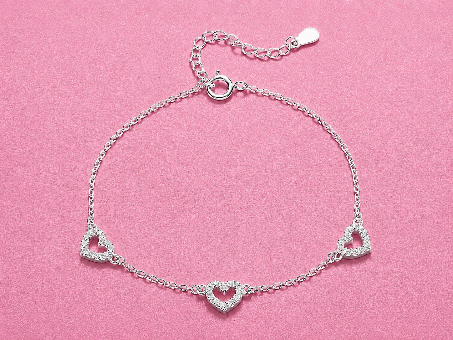 Silver bracelet with heart designs on a pink background
