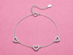 Silver bracelet with heart designs on a pink background
