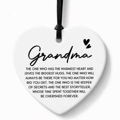 A white heart-shaped ceramic ornament with a black hanging ribbon, featuring the word 'Grandma' in script and a sentimental quote printed below in black text on a light gray background.