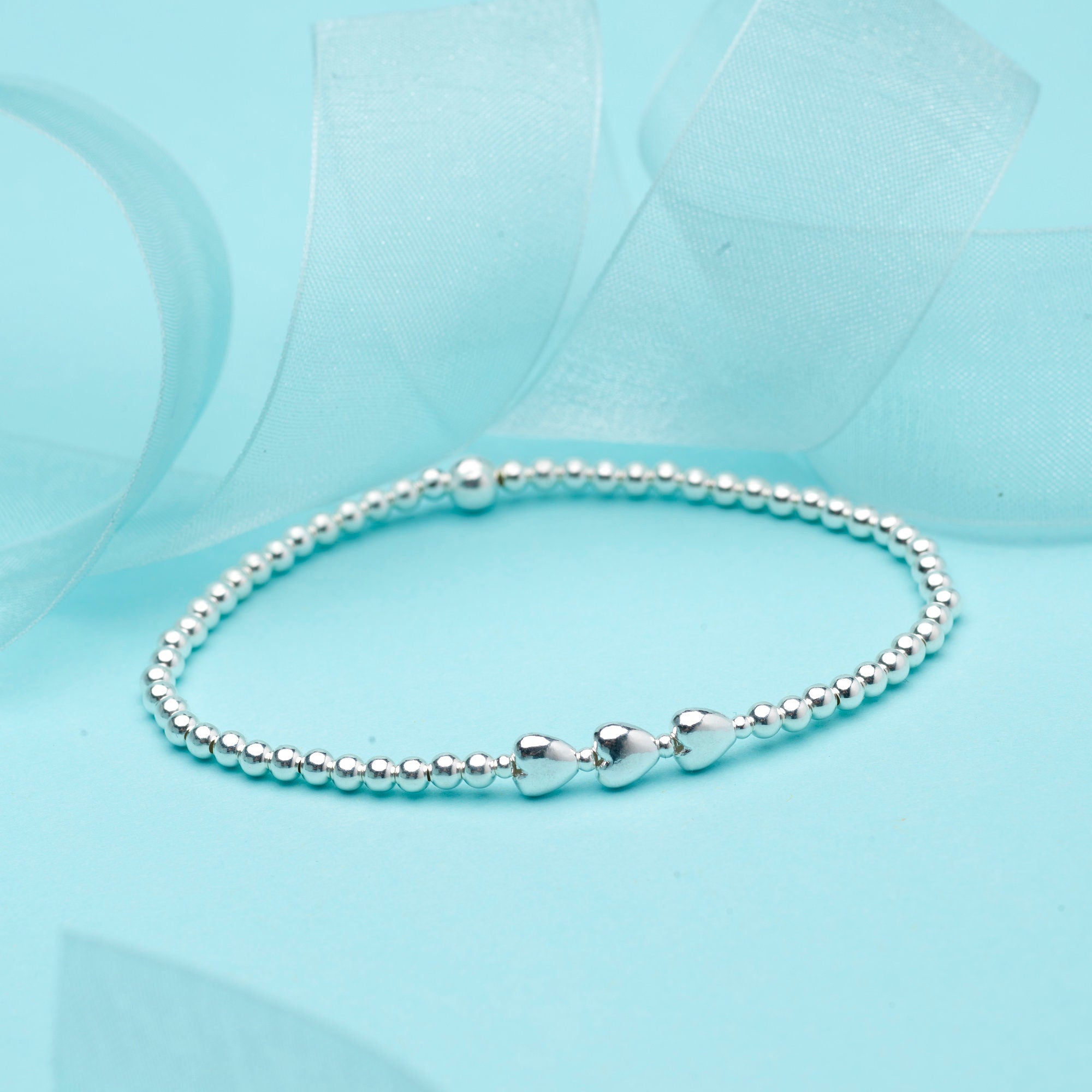 Close-up of Bijou Betty’s 925 silver 30th birthday bracelet with three heart pendants and 3mm beads, stretch-fit.