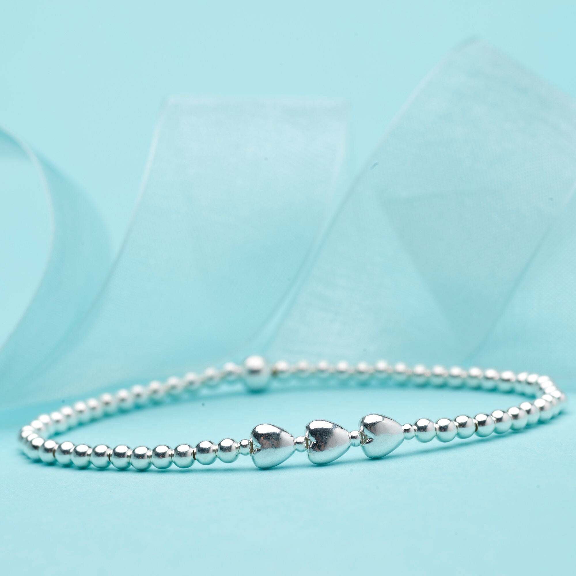 Close-up of Bijou Betty’s 925 silver 30th birthday bracelet with three heart pendants and 3mm beads, stretch-fit.