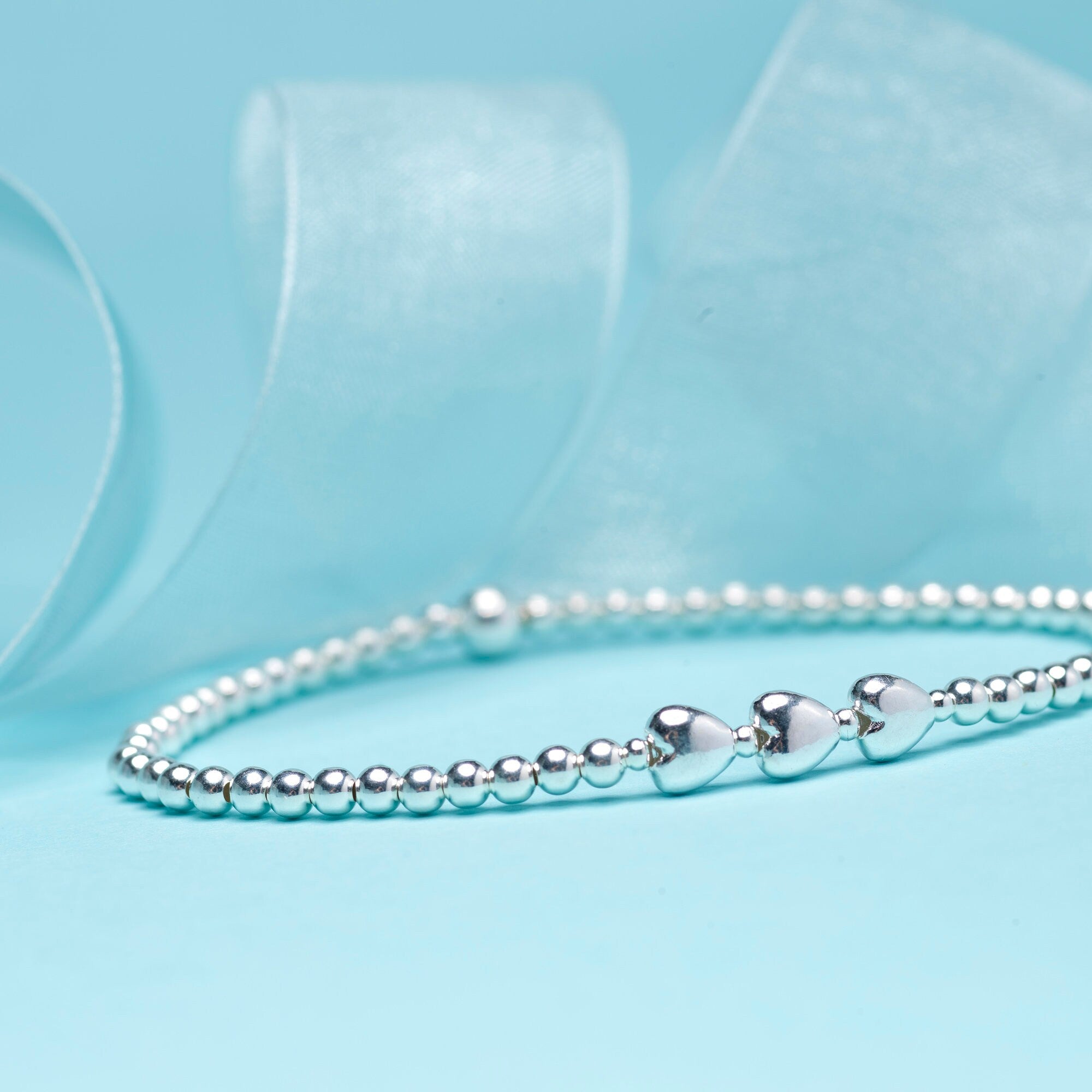 Close-up of Bijou Betty’s 925 silver 30th birthday bracelet with three heart pendants and 3mm beads, stretch-fit.