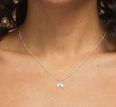 Close-up of model wearing Bijou Betty’s 925 silver angel wing necklace, 9mm x 10mm charm, styled for a comforting tribute.