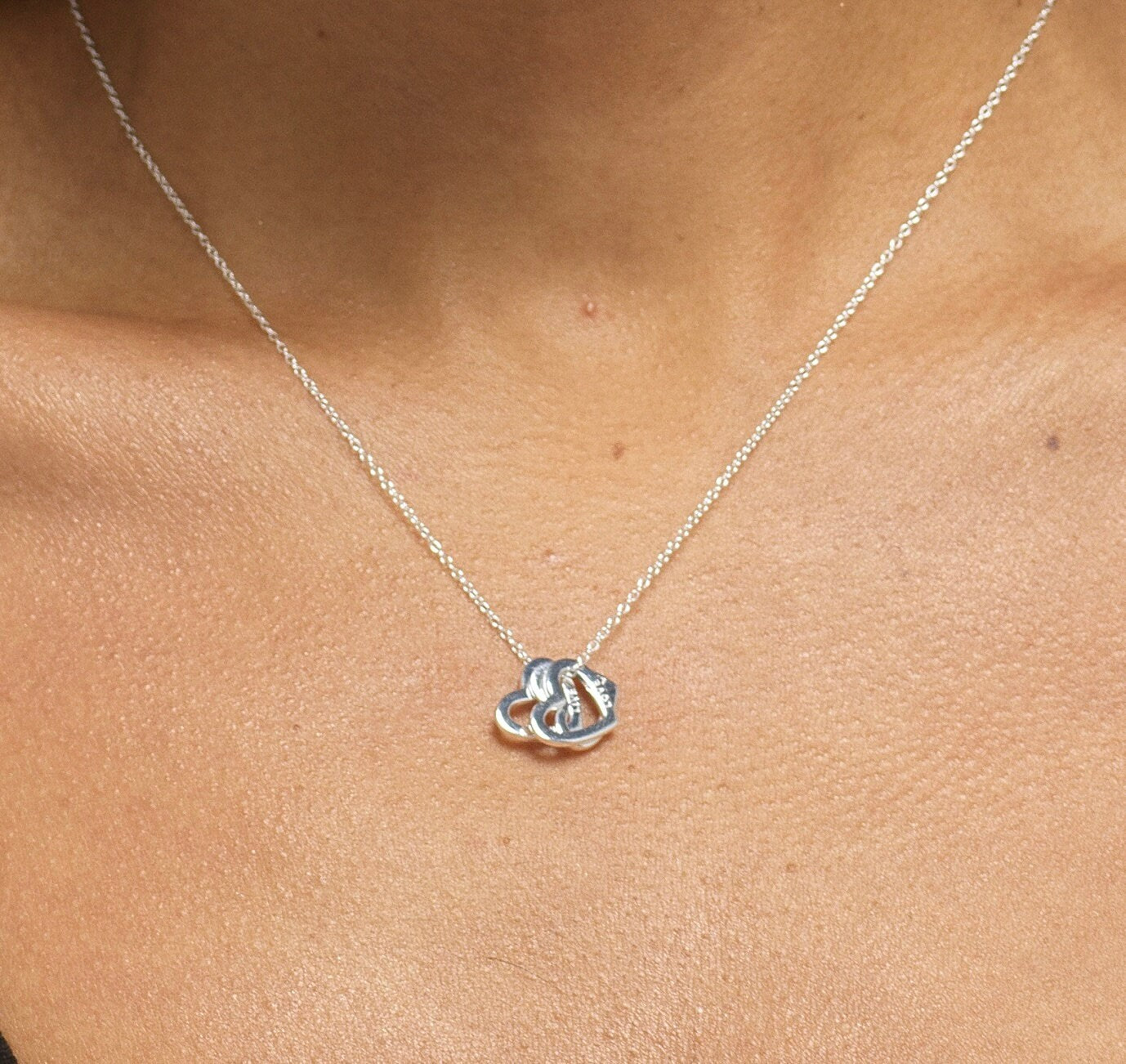 Close up of model wearing Bijou Betty’s 925 sterling silver 18th birthday necklace, featuring three 10mm hearts (“Live, Laugh, Love”) on a 16–18 inch adjustable chain, styled elegantly.