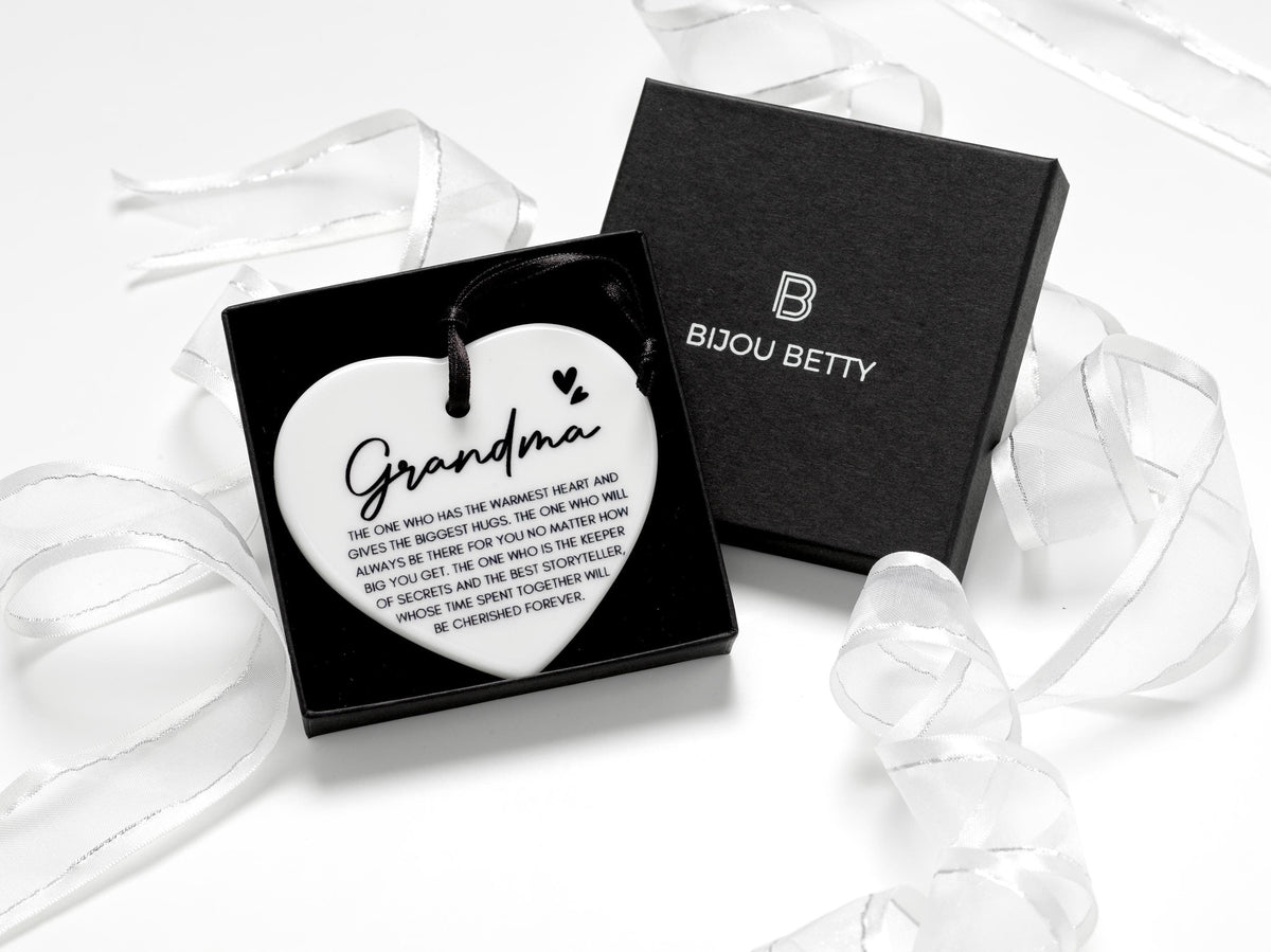 Ceramic heart keepsake with a black satin ribbon, featuring the heartfelt quote, Grandma - The one who has the warmest heart and gives the biggest hugs.  perfect for birthdays, Christmas, or as a sentimental gift for a cherished grandmother.