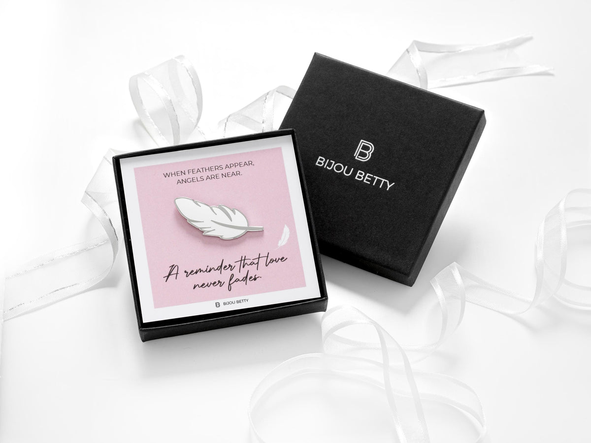 When feathers appear sympathy gift.  A white feather enamel pin badge in a gift box.
