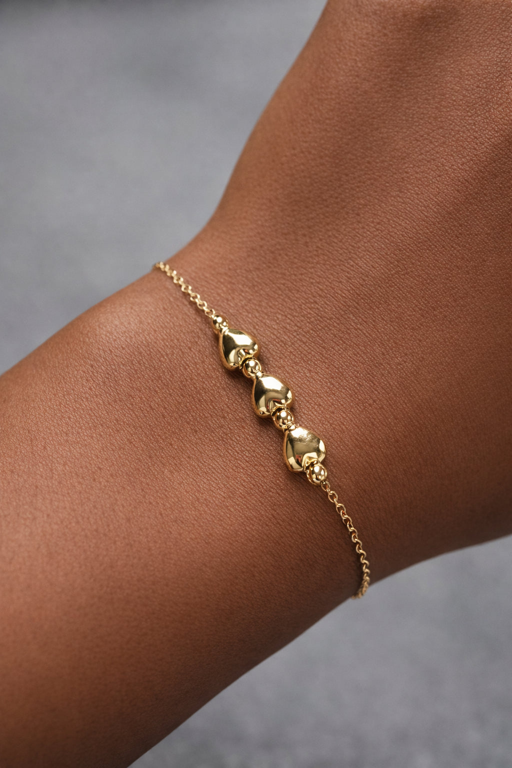 Gold bracelet on a wrist with a neutral background
