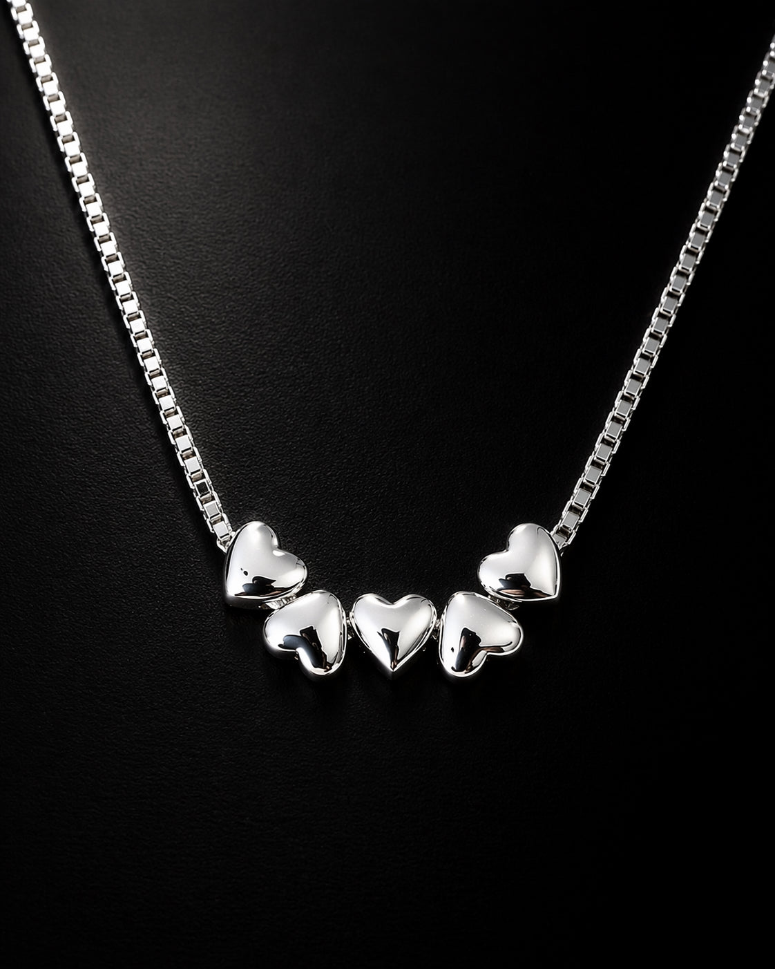 Silver heart-shaped necklace on a black background